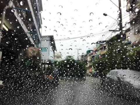 Water drops on a window in the rain. View of car on the street. Stock Photos