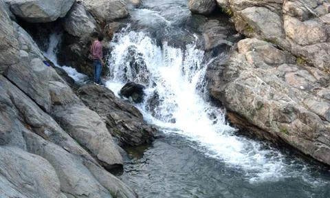 Water falling between the rocks and mixing with a river Stock Photos