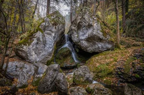 Water falling between two large rocks in autumn forest at Myrafälle Stock Photos