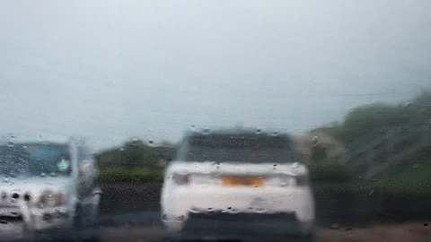 Water falling on a car windscreen in heavy rain with unidentifiable cars ahead Stock Footage 91080136