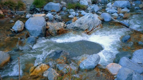 Water falling down the rocks in a mountain river. Big flat rock. Slow motion  Stock Footage 105648073