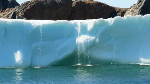 Water falling off of melting ice berg in ocean Stock Footage