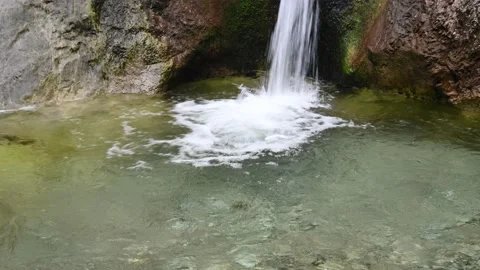 Water falling into a natural pool formed by a mountain stream Video stock 211468330