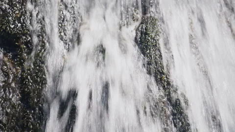 Water falling over a moss-covered rock in a cascading stream outdoors Stock Footage 341645313