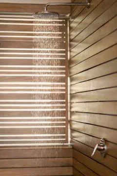 Water falling from rain shower head in wood shower Stock Photos