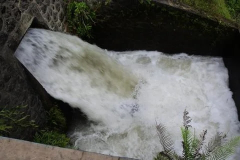 Water falling from a rectangular hole into a pool with white foam 스톡 사진