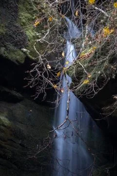 Water falling in a sheet between rocks in a fall mountain landscape Stock Photos