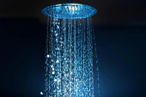 Water falling from the shower on a dark background with blue backlight in the Foto stock