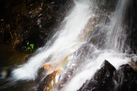 Water falling on stone in the forest black background Stock Photos