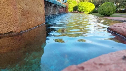 Water falls into a pool that reflects blue sky Stock Footage 259255745