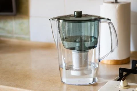 Water filter jug on kitchen table. Clean water concept. Filtration water Stock Photos