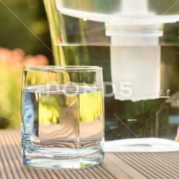 Water filter pitcher and a clean glass of a clear water close up on the summe Stock Photos