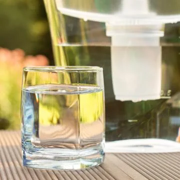 Water filter pitcher and a clean glass of a clear water close up on the summe 写真素材