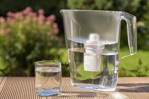 Water filter pitcher and a clean glass of a clear water close up on the summe Photos
