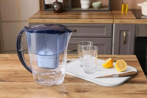 Water filter pitcher with two glasses of filtered water and sliced lemons on  Stock Photos