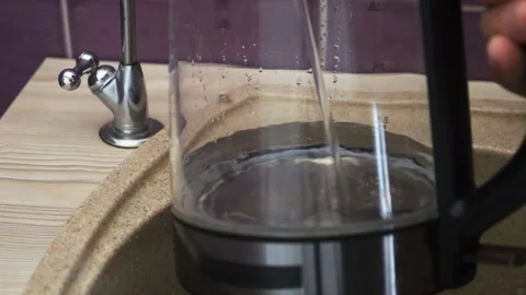 Water from a filter pours in a thin stream from the faucet above the sink i.. Stock Footage 320129194