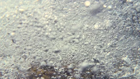 Water flow and air bubbles move beneath the surface after waves strike rocks und Video stock 342139917