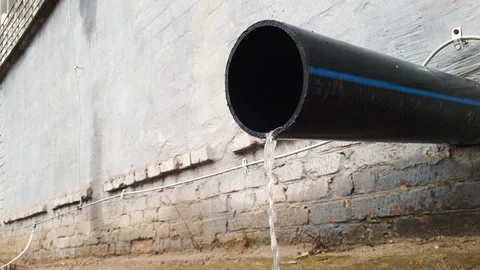 Water flow from black plastic drain pipe on an industrial building after rain Stock Footage 151170326