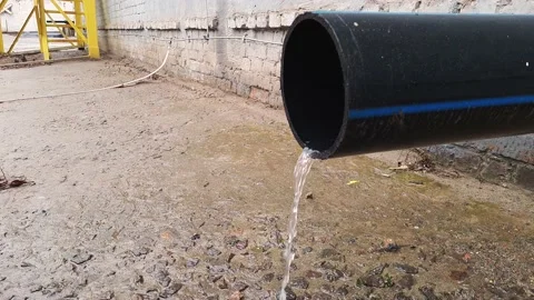 Water flow from black plastic drain pipe on an industrial building after rain Video stock 151245531