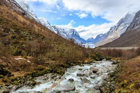 Water flow down from river to lake with snow cap mountain background Stock Photos