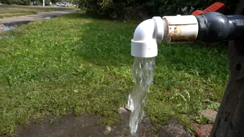 Water flow in slow motion pouring from a garden tap onto grass. Stock Footage 117173842