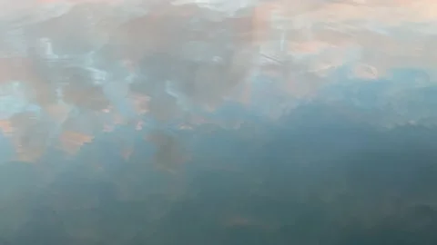 Water flowing with cloud reflection during pastel sunset Stock Footage 225351399