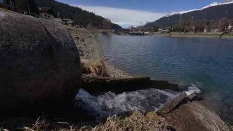 Water flowing from concrete pipe into mountain lake Stock Footage 306656733