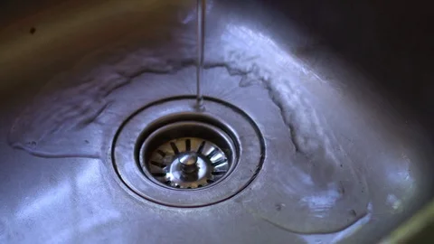 Water flowing down the drain in a shiny stainless steel sink. Video stock 86484922