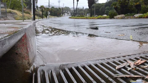 Water flowing down a street gutter into a storm drain after heavy rain in 스톡 동영상 34457805