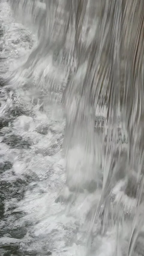 Water flowing down from waterfall pouring into river dynamic texture vertical Stock Footage 246430291