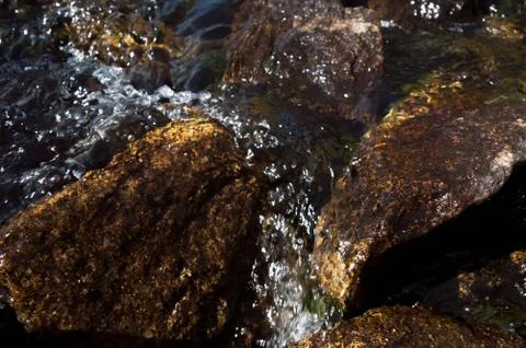 Water flowing downstream between brown rocks. Stock Photos