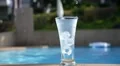 Water Flowing into Glass with Ice near Swimming Pool. Slow Motion. HD Footage