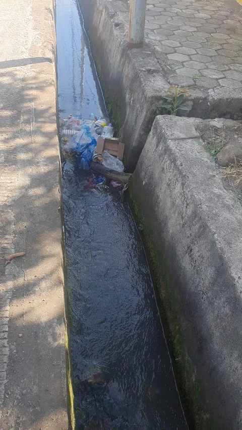 Water flowing in the gutter on the side of the public road Stock Footage 324039994