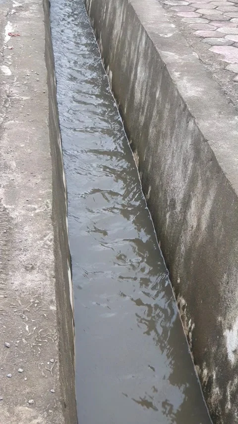 Water flowing in the gutter on the side of the public road Vidéo 332644125