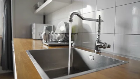 Water flowing out of a kitchen stainless steel tap into the sink. Overusing Stock Footage 142689682