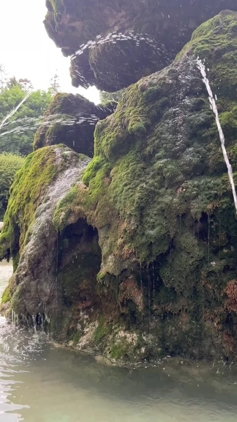 Water flowing over mossy rock with splashes and natural texture detail. The vide Stock Footage 337356282