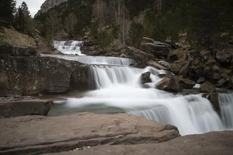 Water flowing over rocks creating tiered waterfalls in pyrenees Stock Photos