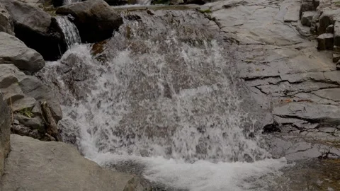 Water flowing over rocks in a small waterfall stream Vidéo 340149240