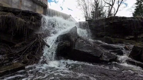 Water flowing over rocky waterfall beneath a small dam, static nature shot Stock Footage 337535822