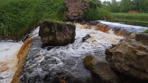 Water flowing over a small man-made waterfall with rocks 库存影片 322646200
