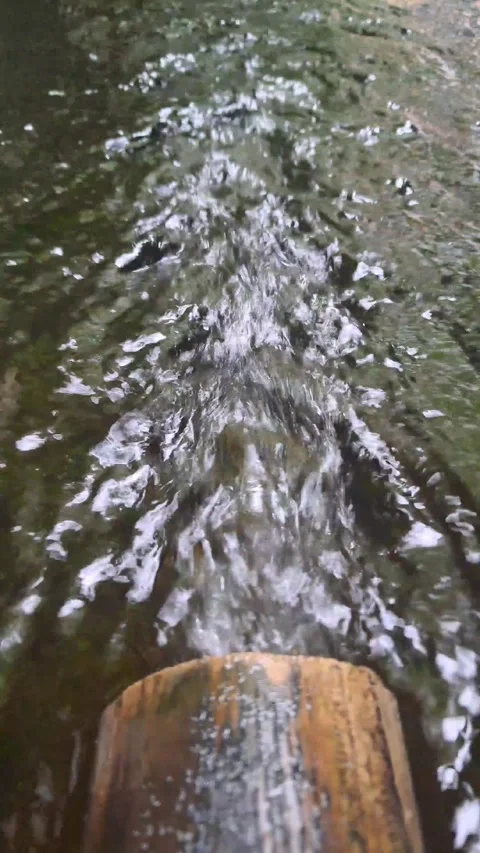 Water flowing rapidly from the end of the bamboo pipe Stock Footage 307035665