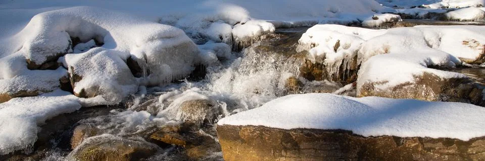 Water flowing in rapids over stone, in the winter mountains Foto stock