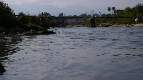 Water flowing in a river with an old bridge made by locals Stock Footage 285699785