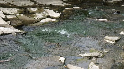 Water flowing into the river with rocks Stock Footage 244707556