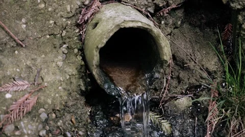 Water is flowing from the sewer pipe outside in the gutter. Close-up shooting Stock Footage 334388671