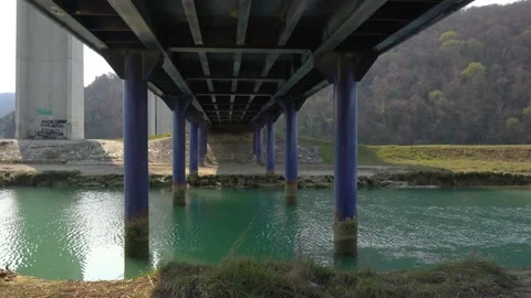 Water flowing under small iron bridge Stock Footage 178133922