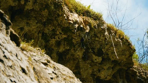 Water flows and drops from steep rock slope. Low angle view on overhang 库存影片 94427478