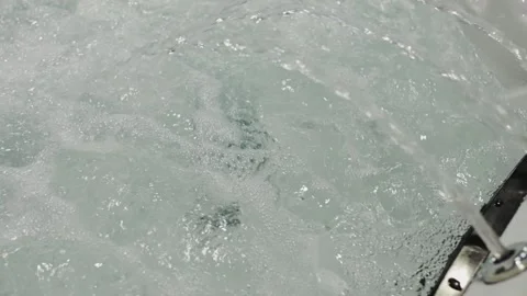 Water flows in a bath with jets for relaxation and comfort in a home setting 库存影片 323935491