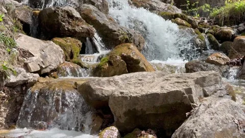 Water flows between large stones of a mountain stream creating natural movement Stock Footage 335584559