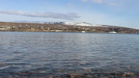 The water flows on the clear transparent lake, colorful stones and snowy hills Stock Footage 233964518